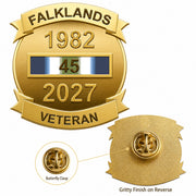 Gold commemorative pin badge reading 'FALKLANDS 1982 2027 VETERAN' with a ribbon bar showing 45 years service, plus inset views of the butterfly clasp and textured reverse side on a white background.